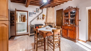 A dining area with a wooden table, chairs, a ceiling fan, and a cabinet. - Apartment 'Sotto Gli Archi' with Mountain View (Civitella Paganico)