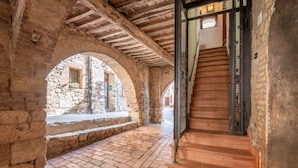 An interior with stone arches, a wooden staircase, and a brick floor. - Apartment 'Sotto Gli Archi' with Mountain View (Civitella Paganico)