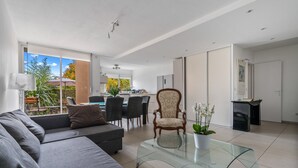 Un salon moderne avec un canapé, une table basse en verre et un coin repas avec des chaises.