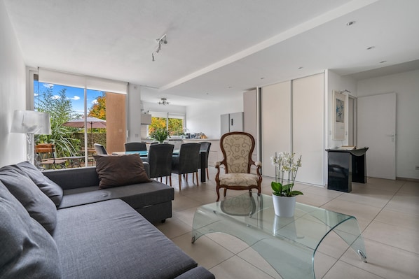 Un salon moderne avec un canapé, une table basse en verre et un coin repas avec des chaises.
