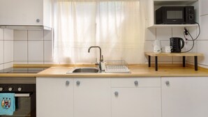 A kitchen with a sink, a microwave, and a shelf with kitchenware. - Holiday Home 'Levada Residence' with Private Terrace, Private Garden and Wi-Fi Access (Funchal)