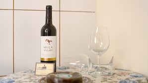 A bottle of wine, a glass, and a plate with a dessert on a table with a floral tablecloth. - Holiday Home 'Levada Residence' with Private Terrace, Private Garden and Wi-Fi Access (Funchal)