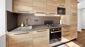 Una cocina moderna con armarios de madera, un lavamanos de acero inoxidable, una estufa a gas y un microondas integrado.