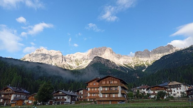 Un pueblo de montaña con edificios tradicionales de madera y vistas a montañas escarpadas.