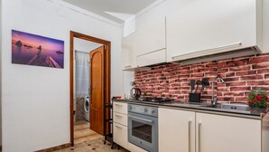 Una cocina con protector contra salpicaduras de ladrillo, armarios blancos, una estufa y un lavabo.