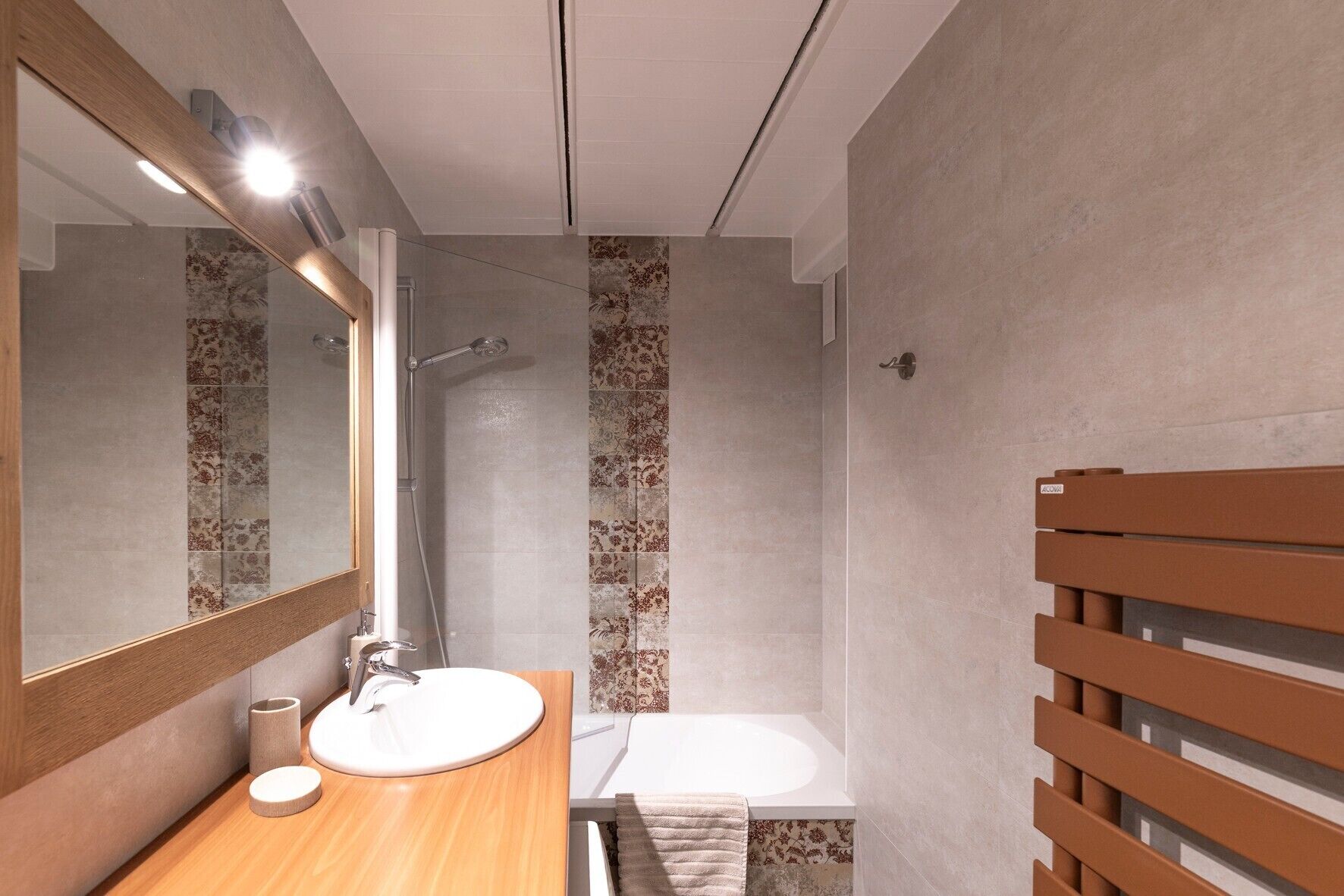 Une salle de bain moderne avec un meuble-lavabo en bois, un grand miroir, une douche et une baignoire.