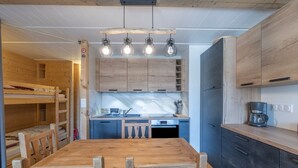A compact kitchen with wooden cabinets, a built-in oven, and a coffee maker. - Flaine Studio J2 Apartment with Mountain View and Wi-Fi (Arâches-la-Frasse)