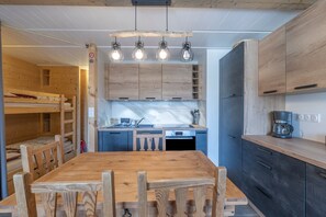 A compact kitchen with wooden cabinets, a built-in oven, and a coffee maker.