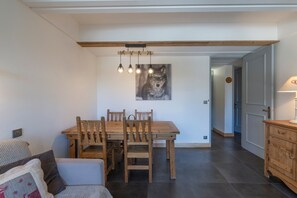 A dining area with a wooden table and chairs, a pendant light, and a wolf painting on the wall.