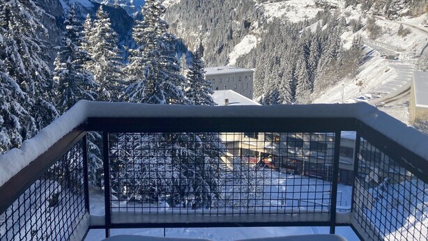 Un paysage de montagne enneigé, avec un bâtiment au premier plan.