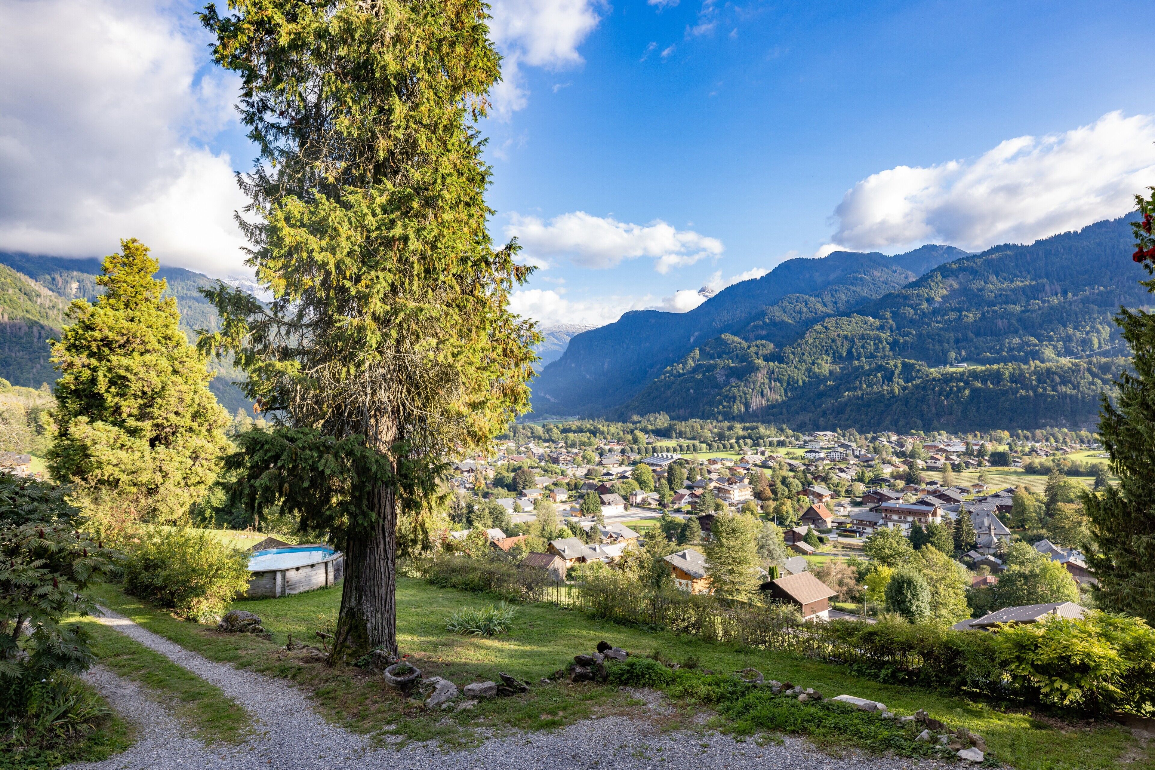 Un village rural avec des maisons, un sentier et des montagnes en arrière-plan.