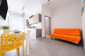 Un soggiorno moderno con un divano, un'area pranzo con tavolo e sedie, una cucina e una porta che conduce in un'altra stanza.