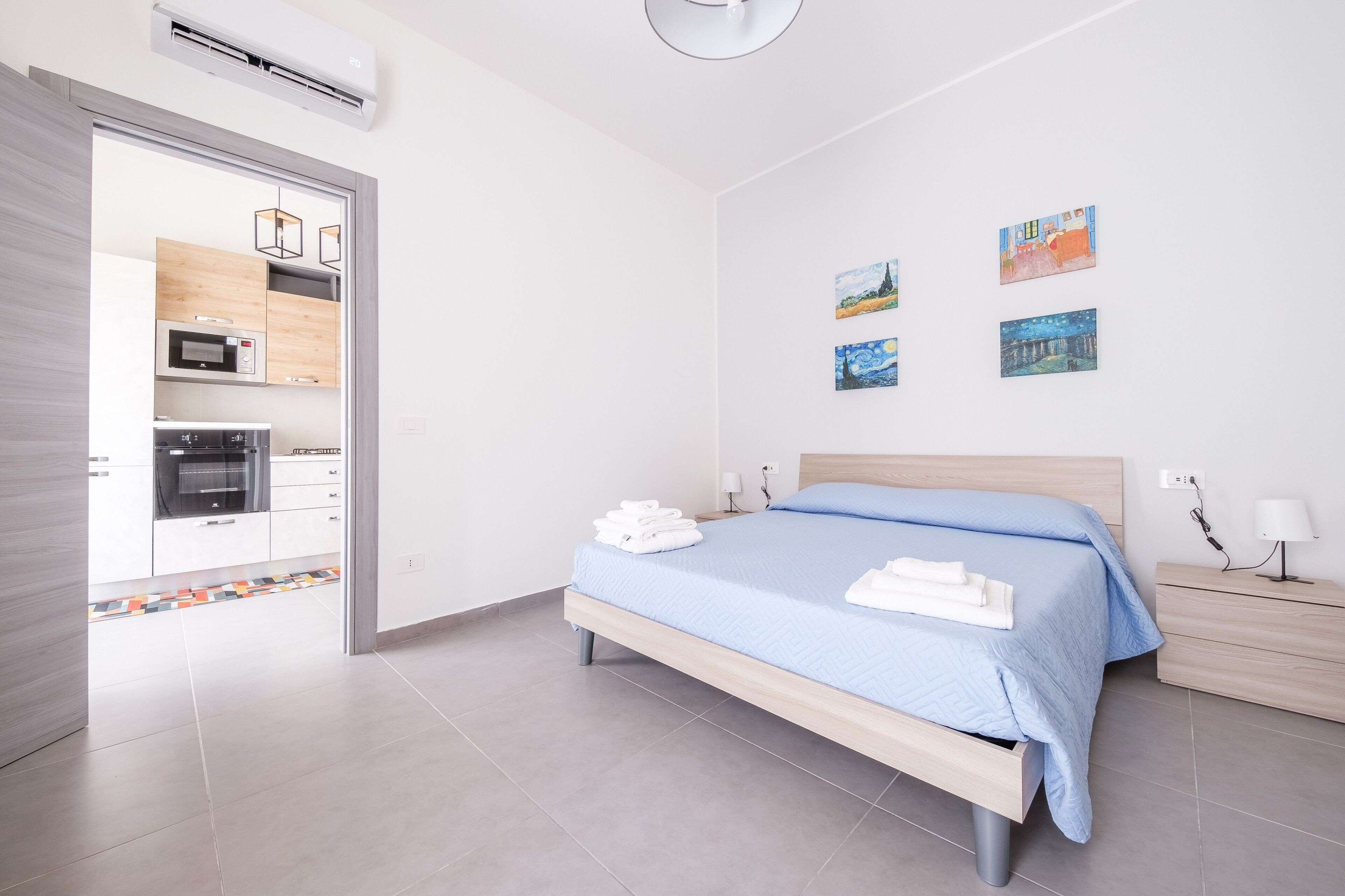 A modern bedroom with a bed, bedside tables, and artwork on the wall.