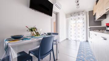 Uma cozinha moderna com uma televisão de tela plana, uma mesa de jantar com cadeiras e um tapete estampado.