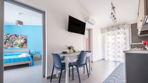 Ein modernes Zimmer mit einem Bett, einem Esstisch mit Stühlen, einem Fernseher und einer Klimaanlage.