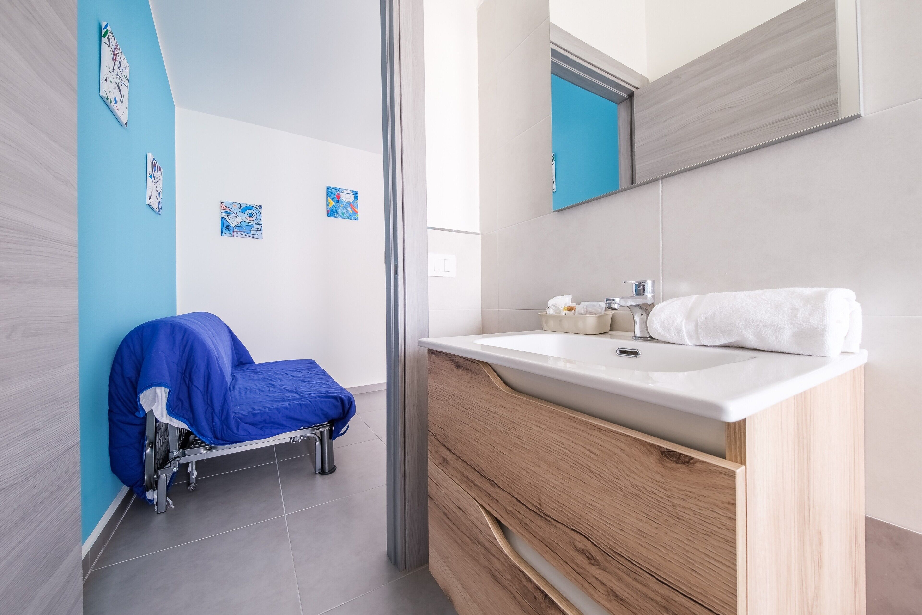 Un baño moderno con tocador de madera, lavabo blanco y pared azul.