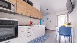 Eine moderne Küche mit integrierten Geräten, Holzschränken und einem Essbereich mit blauem Stuhl und Tisch.
