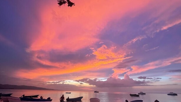 Una playa con barcos y un atardecer.