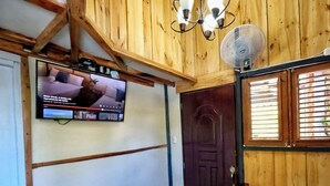 Un interior de madera con un televisor montado en la pared, una puerta y una ventana con persianas.