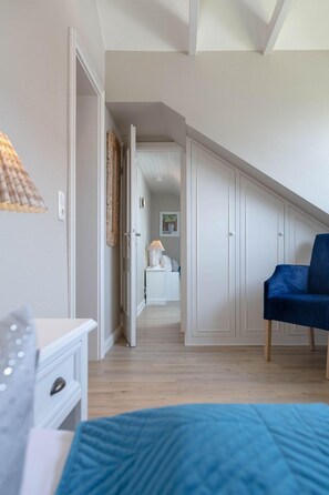 A bedroom with a bed, a chair, a desk, and a wardrobe. - Strand Loft - Ferienwohnung "strand-loft" in Westerland (Sylt)