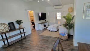 A modern living room with a sofa, a television, and a dining area with a table and chairs.