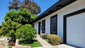 A single-story house with a garage, surrounded by well-maintained landscaping and trees.