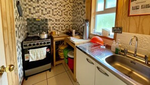 A compact kitchen with a gas stove, a sink, and a window. - Patagonia 47g (Chile Chico)