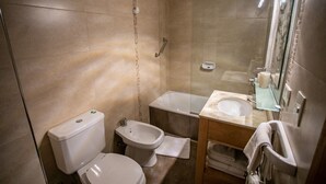 A bathroom with a toilet, bidet, and a sink with a mirror. - BELGRANO SUITE (San Carlos de Bariloche)