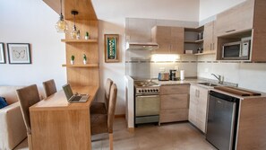 A modern kitchen with wooden cabinets, a stove, a microwave, and a dishwasher. - BELGRANO SUITE (San Carlos de Bariloche)