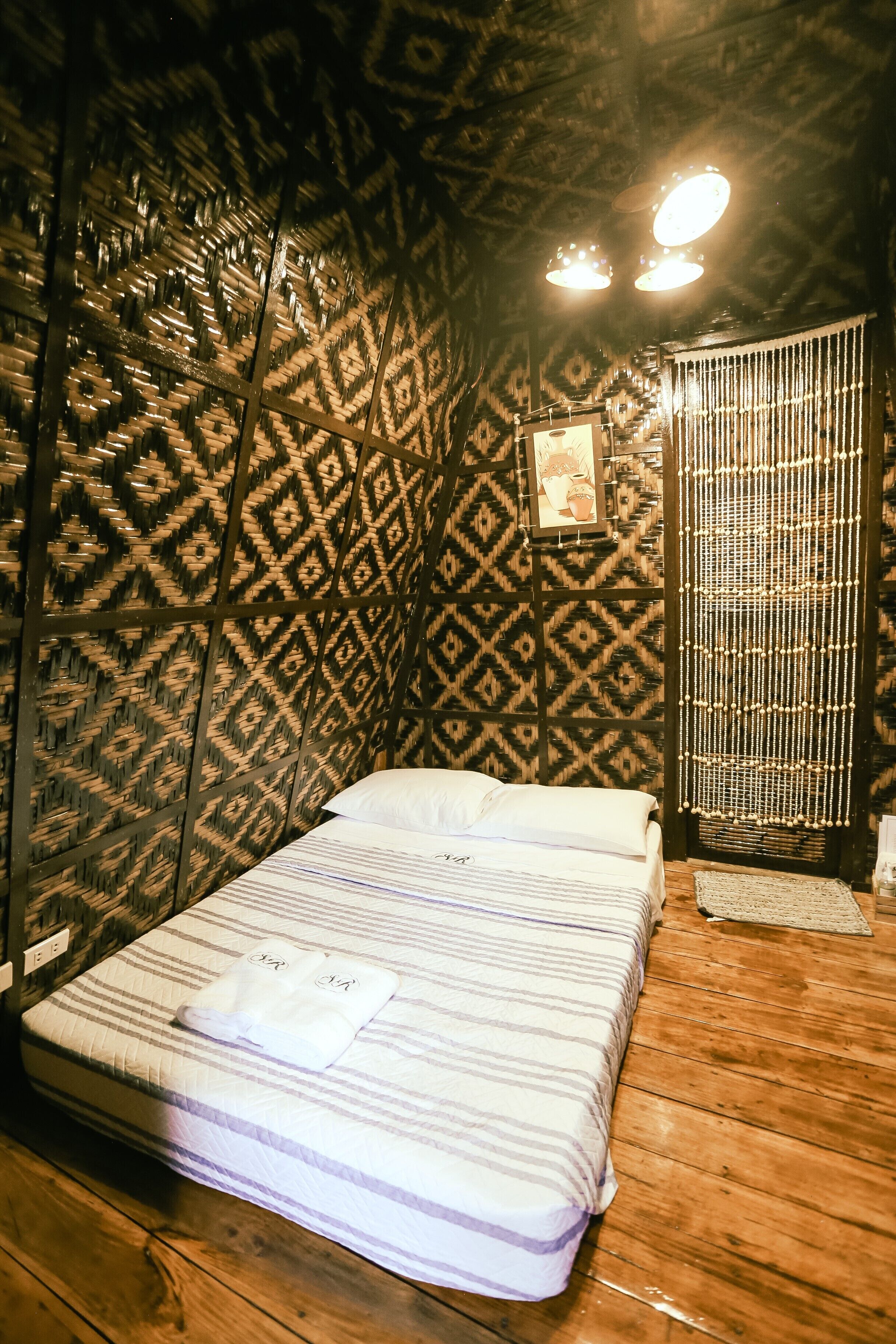 A room with a bed, patterned walls, and a wooden floor.