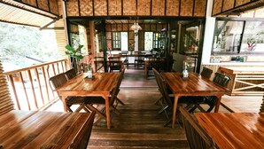 A restaurant with wooden tables and chairs, a central walkway, and large windows. - Shepherd's Ridge Mountain Resort (Mabitac)