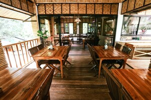 A restaurant with wooden tables and chairs, a central walkway, and large windows.