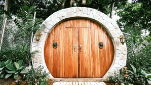 A wooden door with a stone archway, surrounded by lush greenery and a brick pathway. - Shepherd's Ridge Mountain Resort (Mabitac)