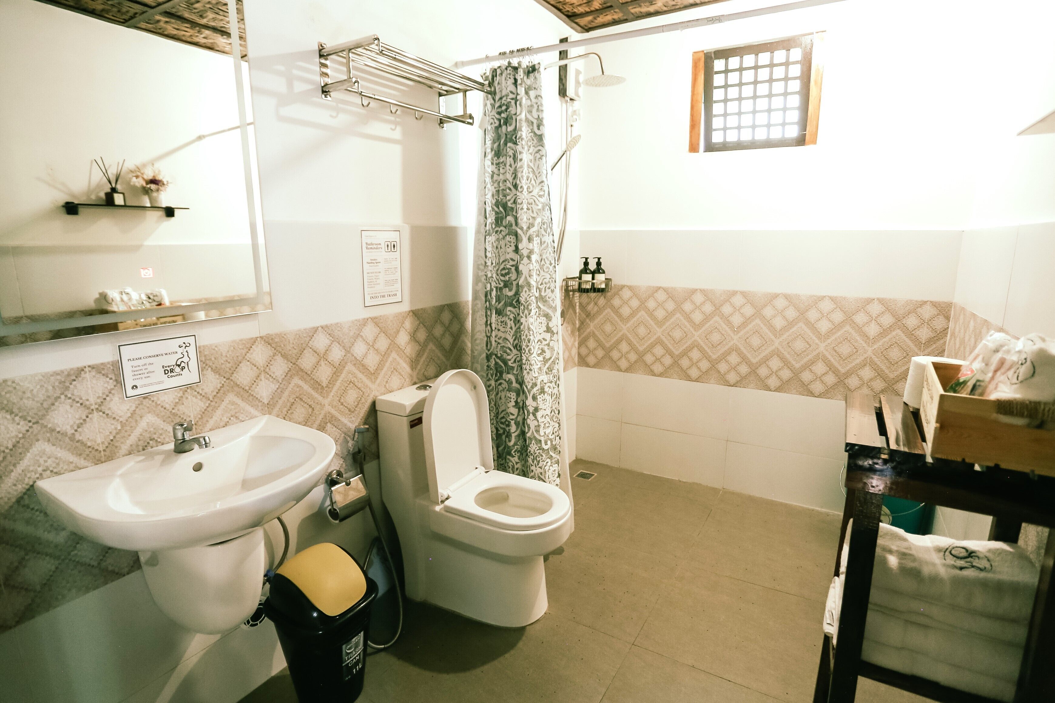 A bathroom with a sink, toilet, shower, and a small window.