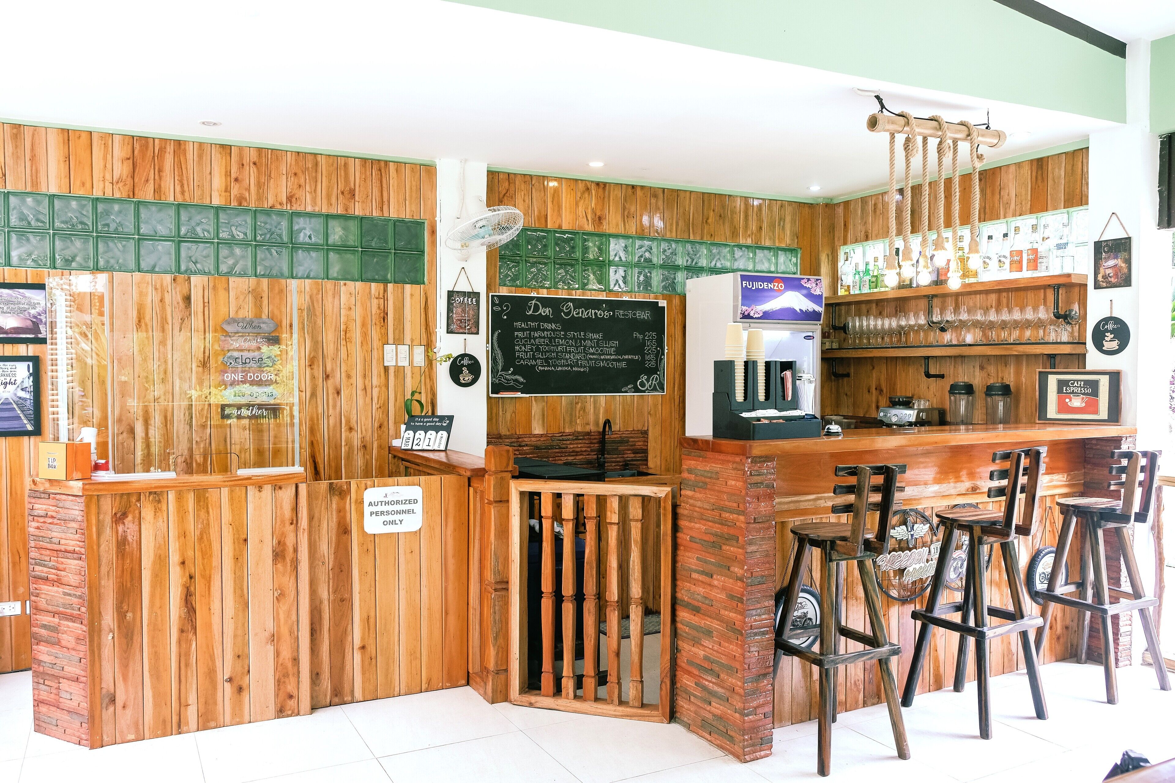 Un café aux murs en bois, avec un coin bar et un tableau affichant le menu.