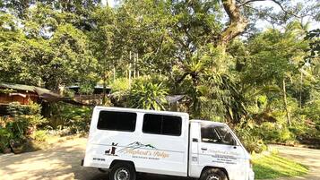 A white van with "Shepherd's Ridge" and "Mountains Resort" branding parked in a lush, green environment.