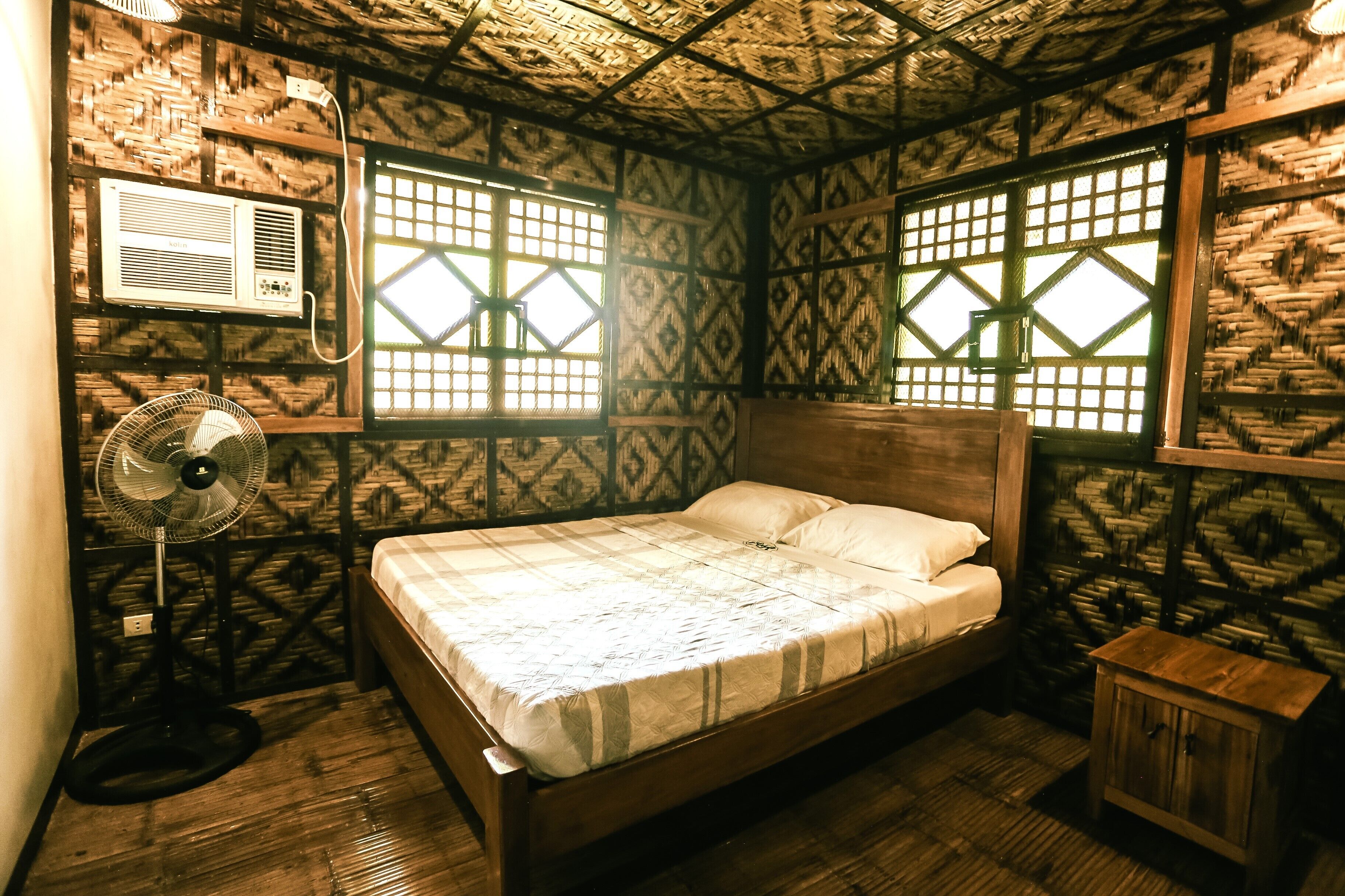 A room with a bed, a fan, and a small cabinet.