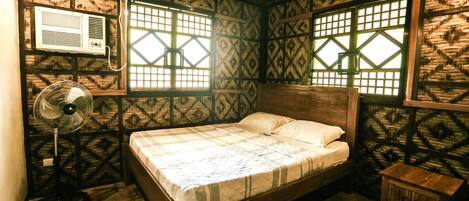 A room with a bed, a fan, and a small cabinet.