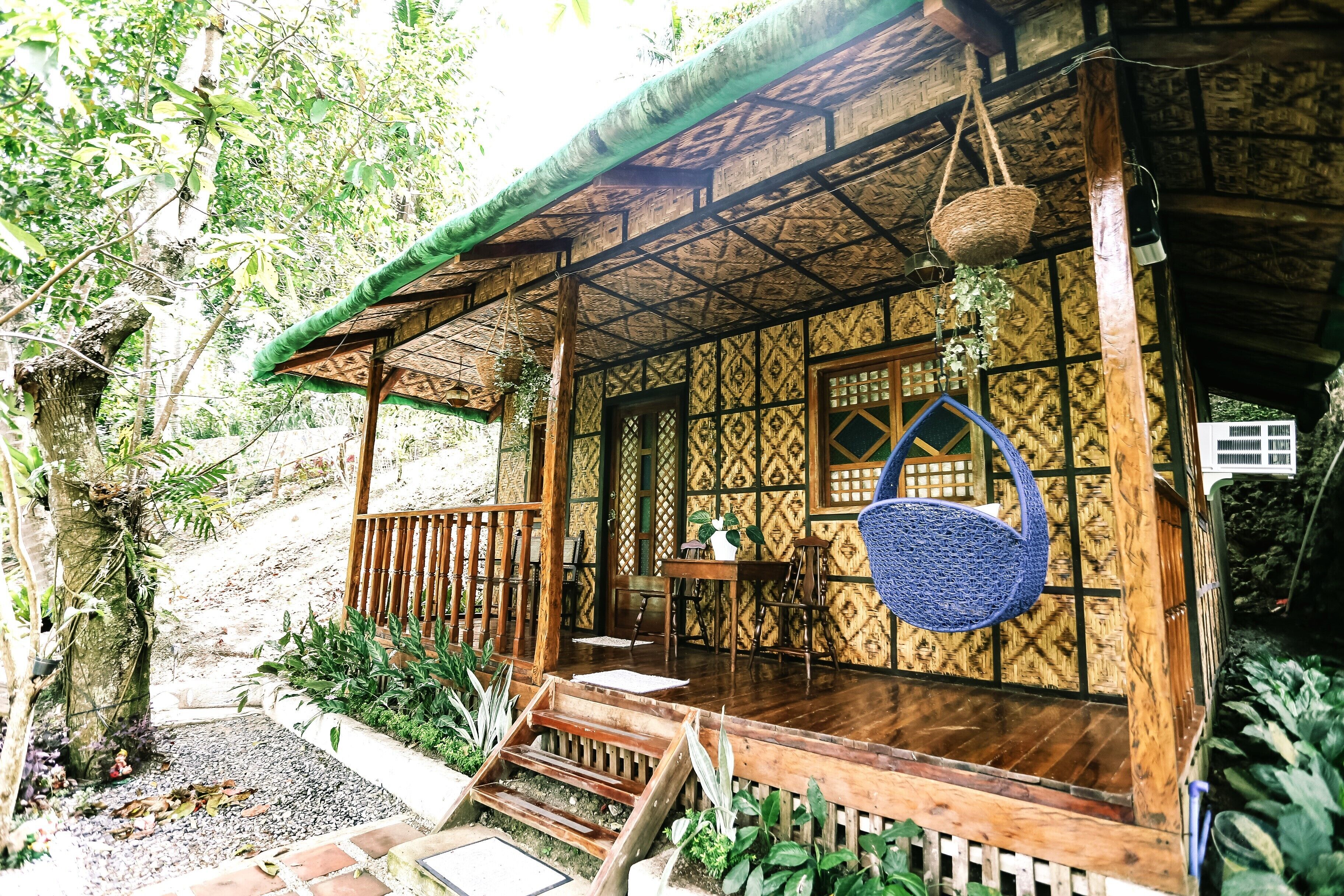 A wooden structure with a thatched roof, a wooden deck, and a hanging basket.