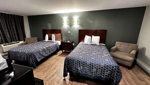 A hotel room with two beds, a desk, a chair, and a nightstand.
