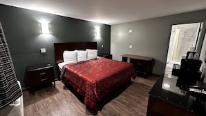 A hotel room with a bed, bedside tables, a desk, and a mirror.