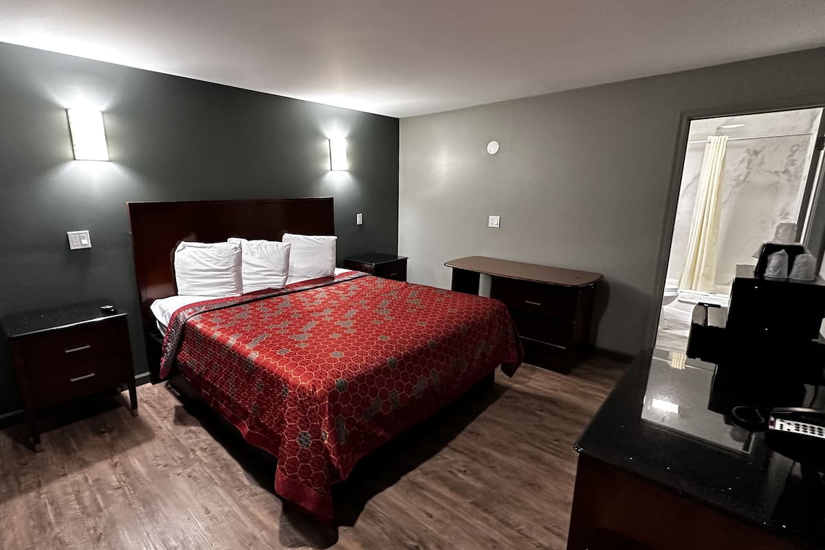 A hotel room with a bed, bedside tables, a desk, and a mirror.