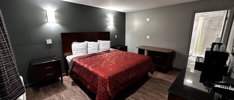 Ein Hotelzimmer mit Bett, Nachttischen, Schreibtisch und Spiegel.