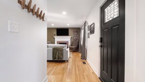 A hallway with a fireplace, a sofa, and a black door.