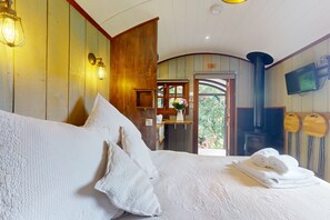 A cozy room with a large bed, wooden walls, a fireplace, and a television.