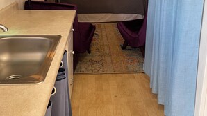A compact room with a bed, a small sink, a mirror, a ceiling fan, and a window with curtains. - Secret Garden in gorgeous Sedona with AC, WiFi (Sedona)