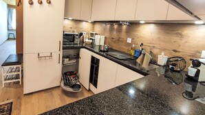 A modern kitchen with white cabinets, a black countertop, and a wooden backsplash.