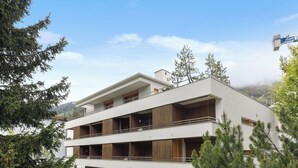 A modern multi-story building with a flat roof, balconies, and wooden paneling.