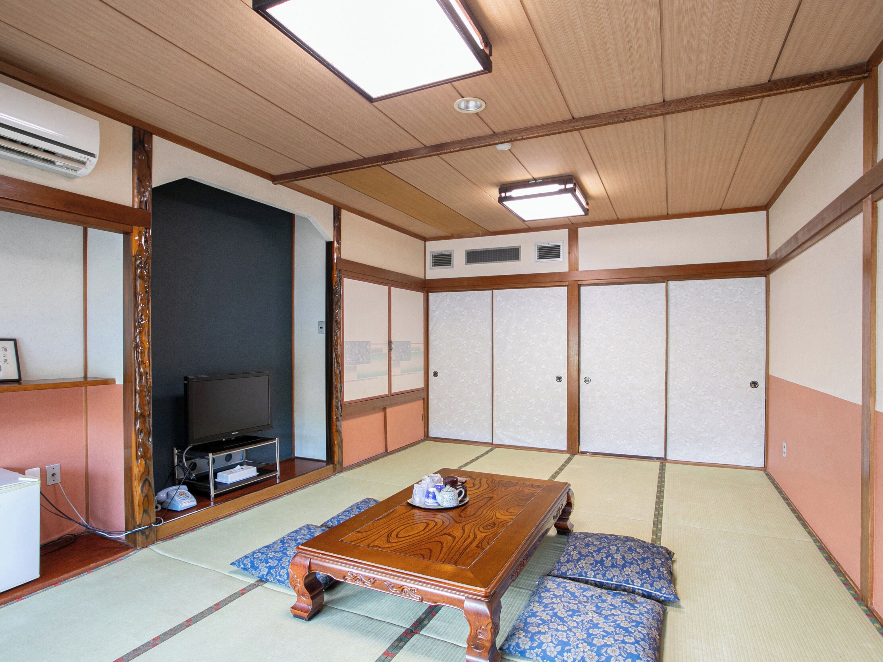 Una habitación japonesa tradicional con suelo de tatami, una mesa de madera y puertas correderas.