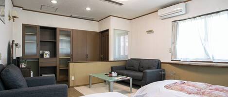 A hotel room with two beds, a sofa, a small table, and a cabinet.